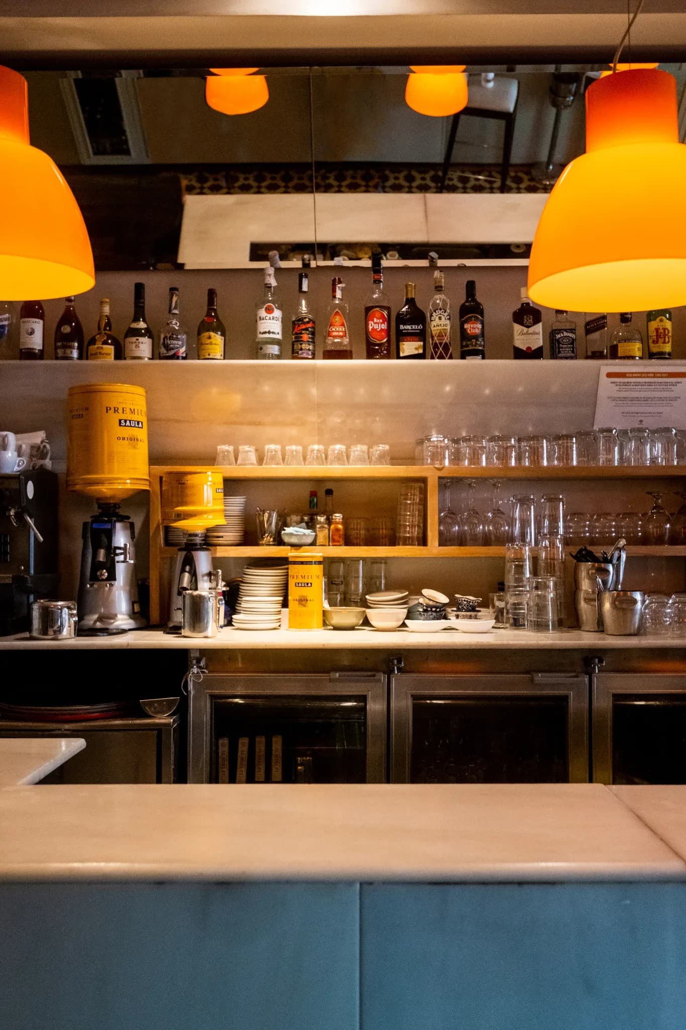 Barra interior de Restaurante Igueldo en España, con botellas, cafetera y lámparas naranjas sobre la zona de servicio