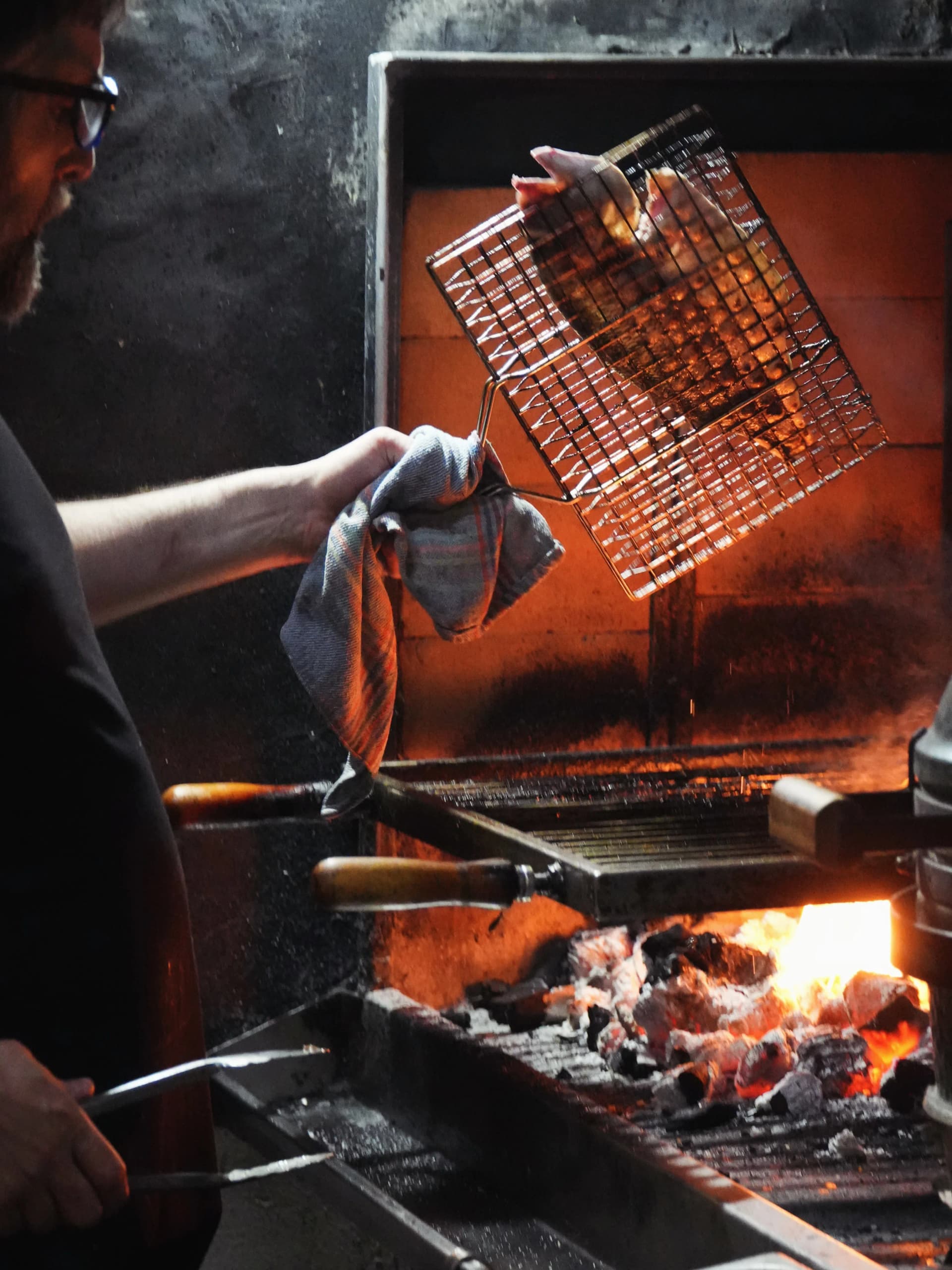 Cocinero trabajando en la parrilla de carbón del Restaurante Igueldo en Barcelona, brasas encendidas para carnes y pescados a la brasa