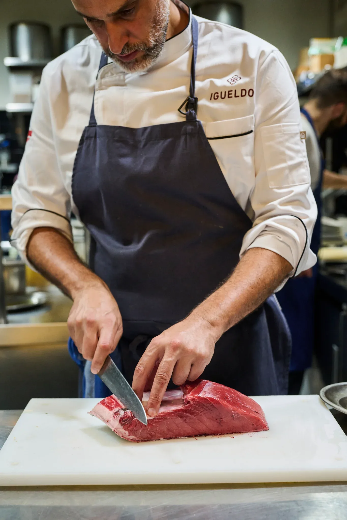 Cocinero del Restaurante Igueldo en España cortando una gran pieza de chuletón de vaca en la cocina profesional