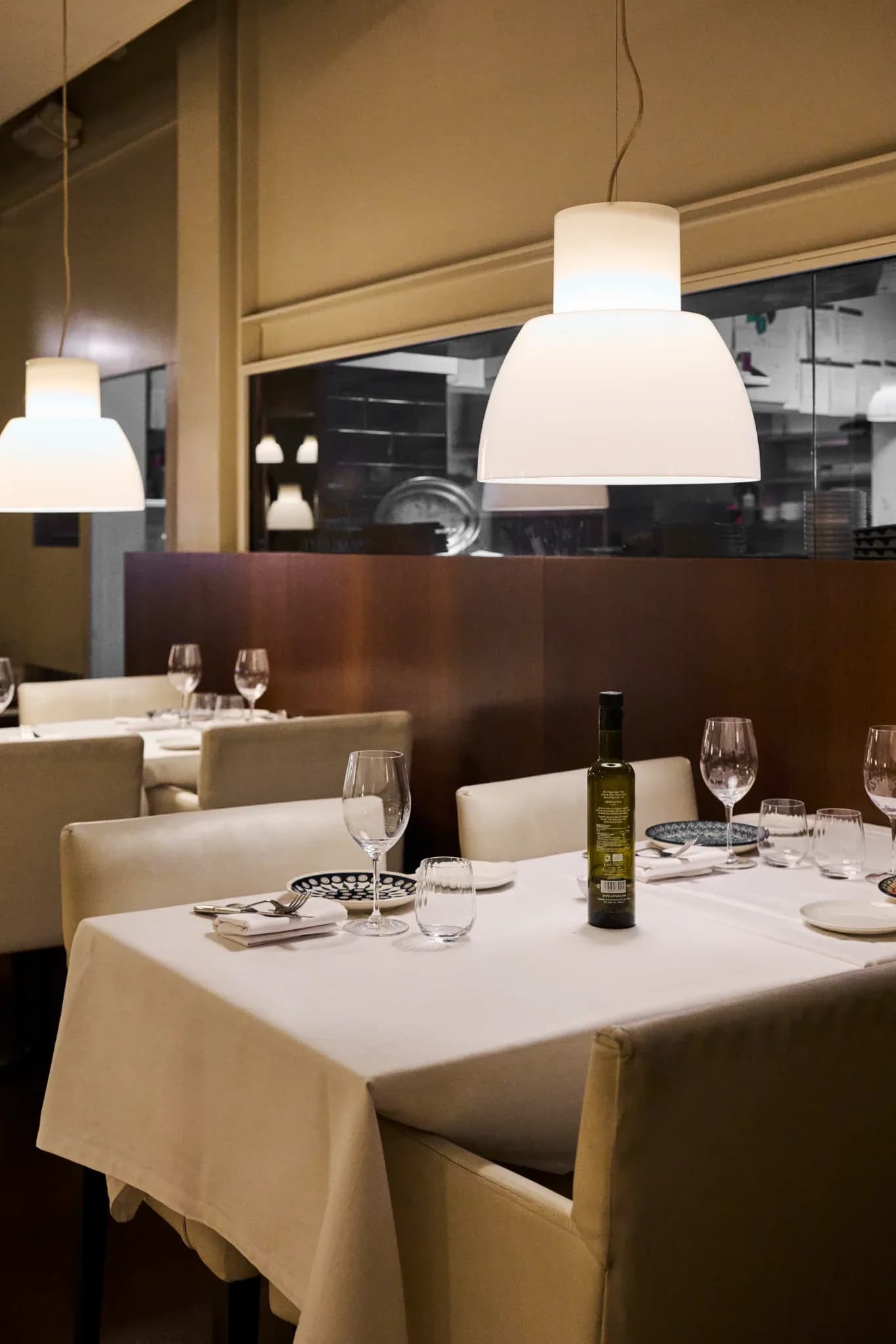 Mesa elegante preparada con copas y botella de aceite en el comedor interior de Restaurante Igueldo en Barcelona