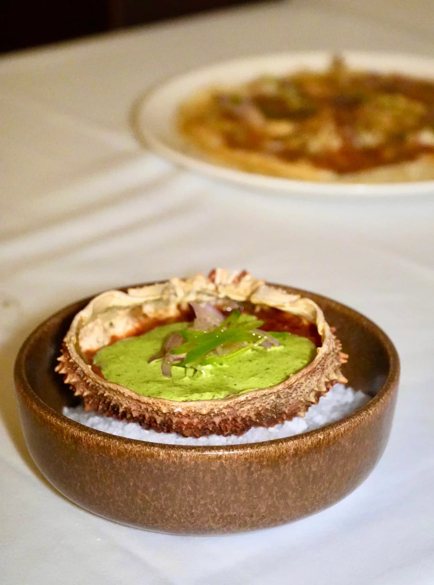 Tapa de marisco servida en el caparazón con salsa verde cremosa en Restaurante Igueldo, cocina de tapas en Barcelona