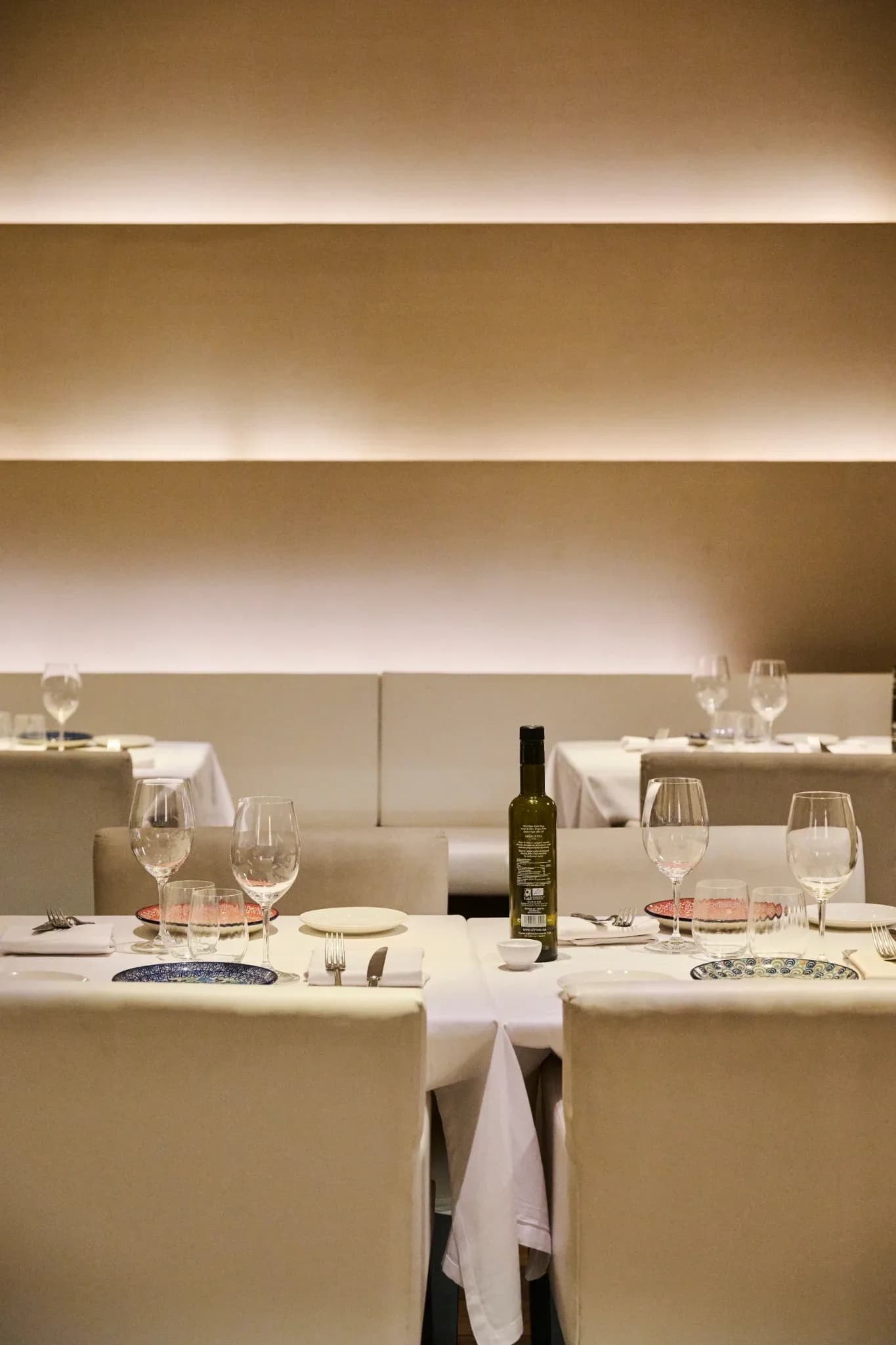 Interior del comedor de Restaurante Igueldo en Barcelona, mesas elegantes con copas de vino y luz cálida en la pared